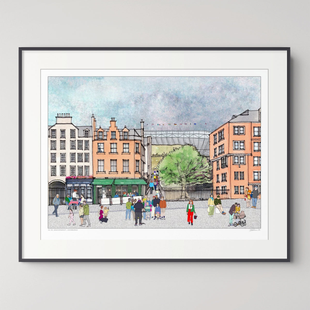 A framed watercolour-style art print depicting Edinburgh Grassmarket with buildings, pedestrians, and a green tree, shown against a light grey wall.