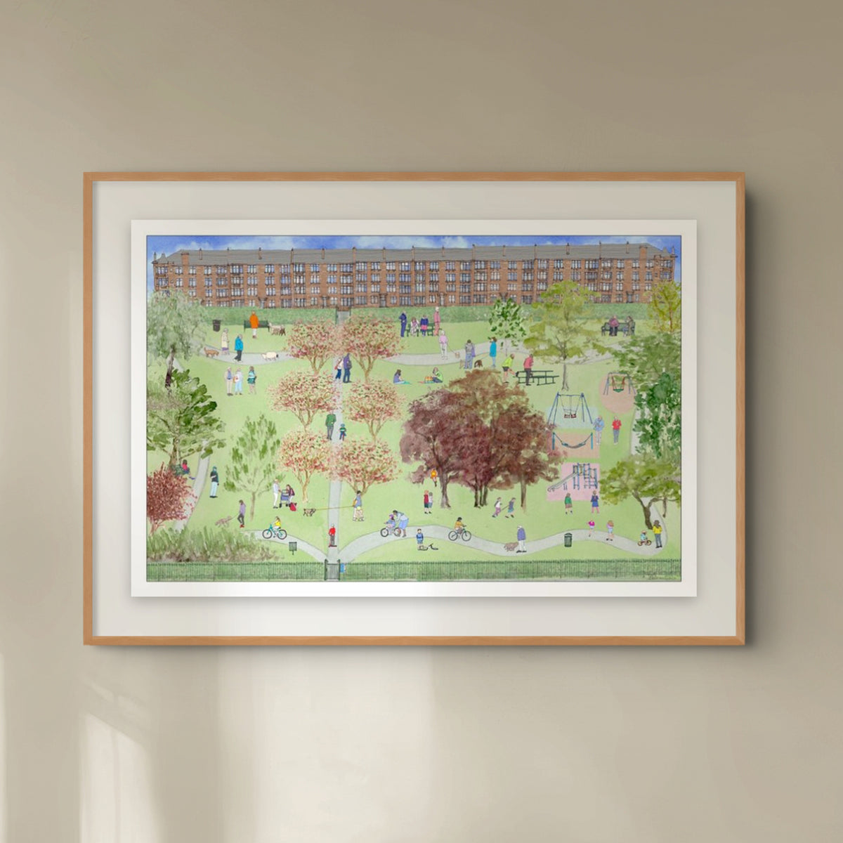 A framed art print depicting a vibrant, detailed illustration of Naseby Park in Glasgow with people, trees, and a large sandstone apartment building in the background, mounted on a beige wall.