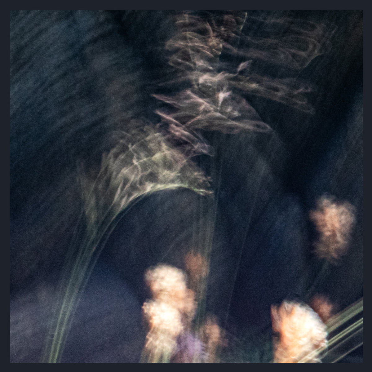 Abstract photographic print featuring blurred light trails and soft glowing shapes in dark blue, black, and pale peach tones.