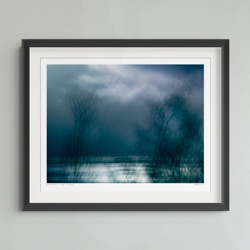 Dark blue and teal abstract landscape artwork with a bright white horizontal band across the lower middle and silhouetted tree branches across the right side.