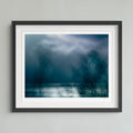 Dark blue and teal abstract landscape artwork with a bright white horizontal band across the lower middle and silhouetted tree branches across the right side.